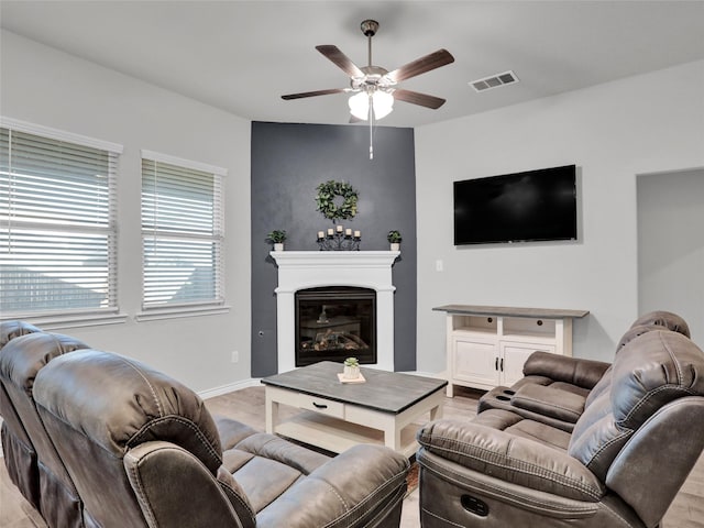 living room featuring a large fireplace and ceiling fan