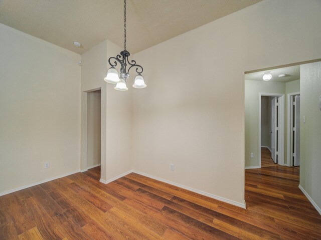 unfurnished room with dark wood-type flooring and an inviting chandelier