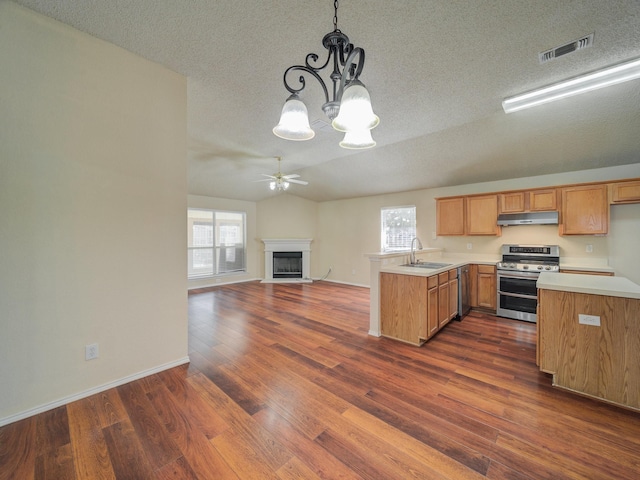 kitchen featuring sink, hanging light fixtures, stainless steel range oven, kitchen peninsula, and a textured ceiling