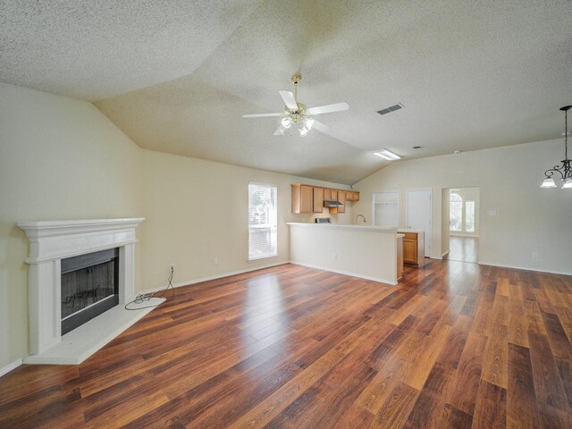 unfurnished living room with dark wood-type flooring, vaulted ceiling, a textured ceiling, and ceiling fan with notable chandelier