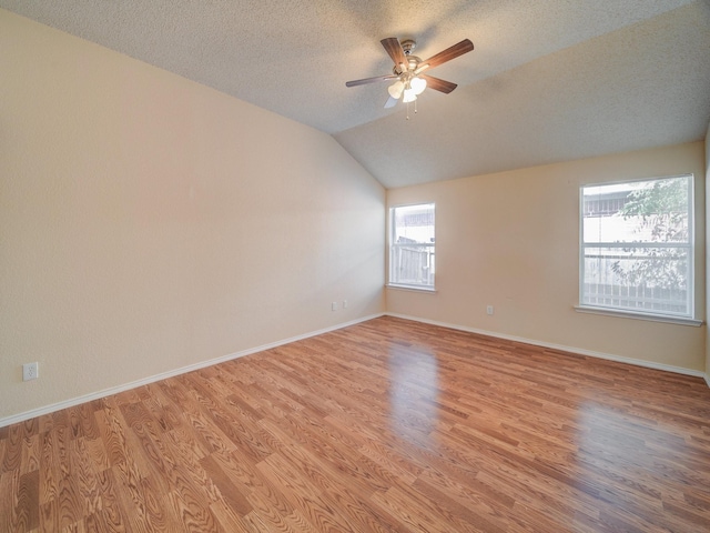 spare room featuring ceiling fan, light hardwood / wood-style flooring, a textured ceiling, and vaulted ceiling