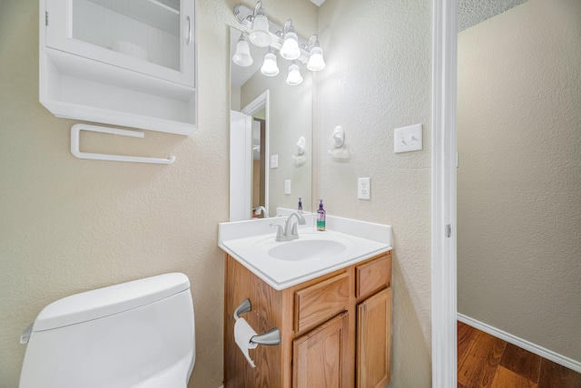 bathroom with toilet, vanity, and hardwood / wood-style flooring