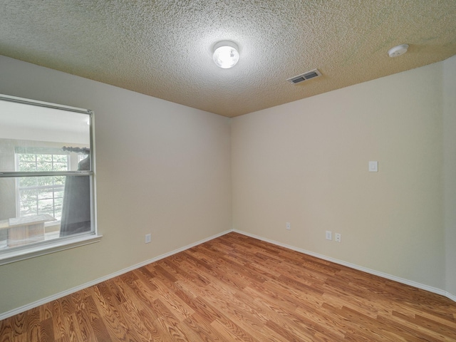 unfurnished room with light hardwood / wood-style flooring and a textured ceiling