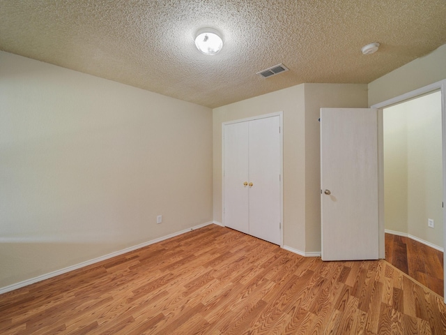 unfurnished bedroom with a textured ceiling, a closet, and light wood-type flooring