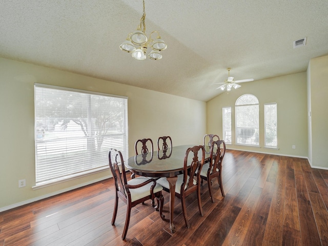 dining space with vaulted ceiling, dark hardwood / wood-style floors, ceiling fan with notable chandelier, and a textured ceiling