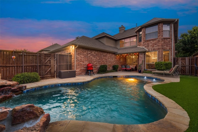 pool at dusk featuring pool water feature and a patio area