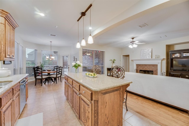 kitchen with a center island, stainless steel dishwasher, decorative light fixtures, a breakfast bar area, and a fireplace