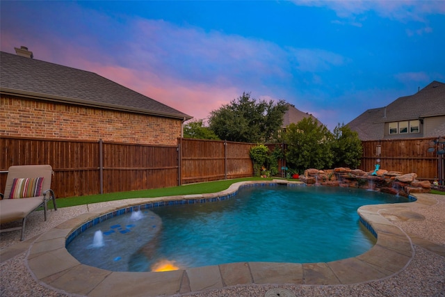 pool at dusk featuring pool water feature