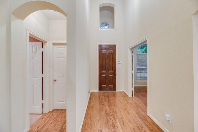 corridor with a high ceiling and light wood-type flooring