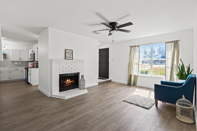 living room featuring ceiling fan, a fireplace, and dark hardwood / wood-style floors