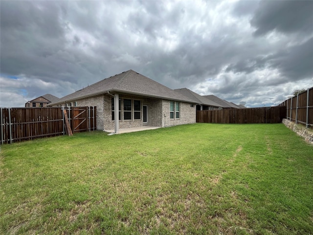 back of house featuring brick siding, a lawn, a fenced backyard, and a patio