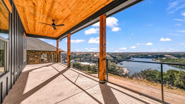 unfurnished living room featuring ceiling fan, a stone fireplace, a water view, and light wood-type flooring