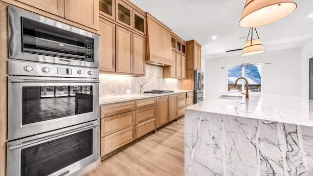 kitchen featuring stainless steel appliances, backsplash, a sink, and light stone countertops