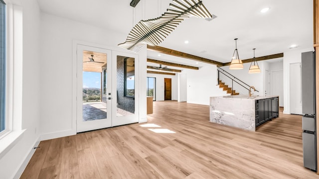 interior space featuring french doors, stairway, a sink, light wood-type flooring, and beamed ceiling