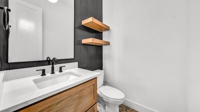 bathroom featuring baseboards, vanity, and toilet