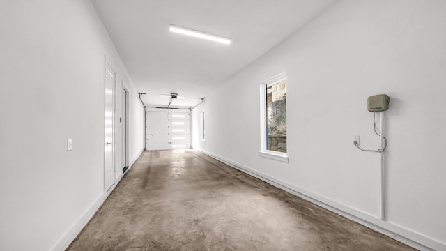 hall with baseboards and finished concrete floors