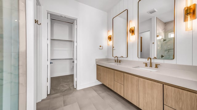 bathroom featuring a shower stall, a spacious closet, visible vents, and a sink