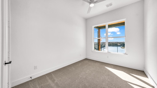 carpeted empty room featuring baseboards, visible vents, and a ceiling fan