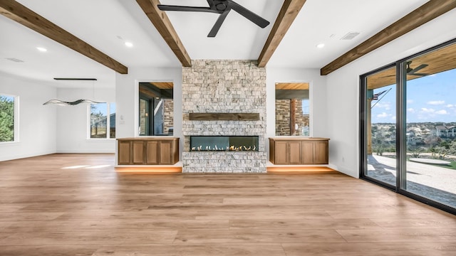 unfurnished living room with baseboards, a fireplace, visible vents, and light wood-style floors