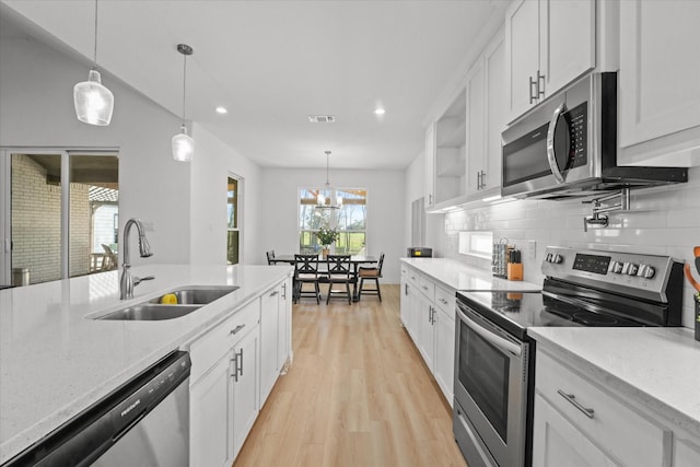 kitchen with hanging light fixtures, white cabinets, stainless steel appliances, and sink