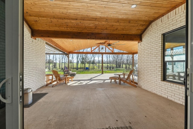 view of patio featuring wood ceiling, ceiling fan, a healthy amount of sunlight, and vaulted ceiling with beams