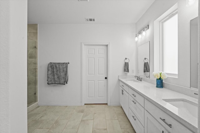 bathroom featuring vanity, a healthy amount of sunlight, and a shower with shower door