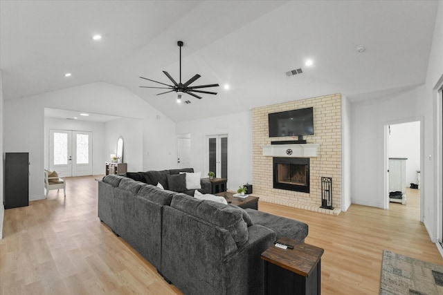 living room featuring lofted ceiling, french doors, ceiling fan, light wood-type flooring, and a fireplace