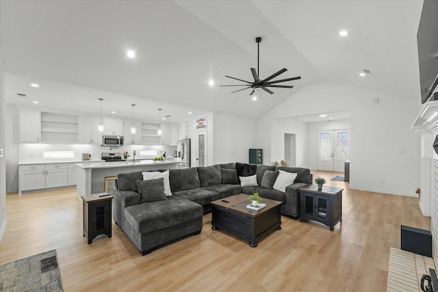 living room featuring lofted ceiling, french doors, sink, ceiling fan, and light wood-type flooring