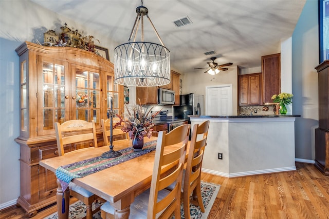 dining space featuring light wood-style floors, baseboards, visible vents, and ceiling fan with notable chandelier