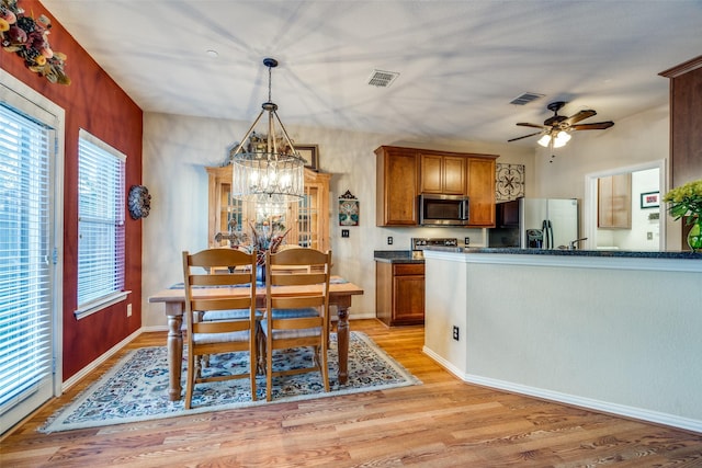 dining area featuring ceiling fan with notable chandelier, light wood-type flooring, visible vents, and baseboards