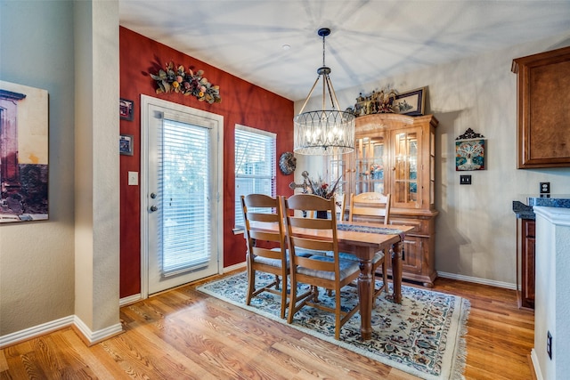 dining room featuring light wood-type flooring, baseboards, and an inviting chandelier