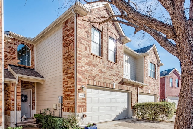 view of property with an attached garage, driveway, and brick siding