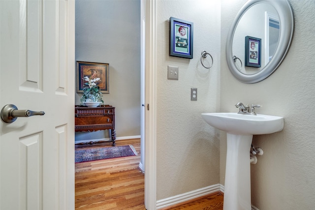 bathroom featuring a textured wall, wood finished floors, and baseboards