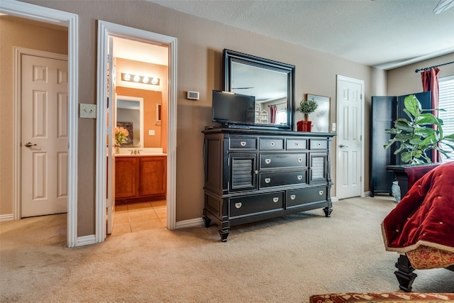 bedroom with carpet, a textured ceiling, baseboards, and ensuite bathroom