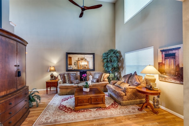 living area with baseboards, a high ceiling, and wood finished floors