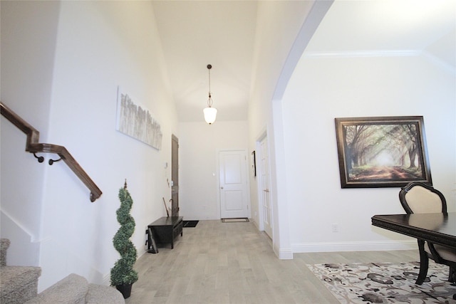 foyer featuring light wood-type flooring, ornamental molding, and vaulted ceiling