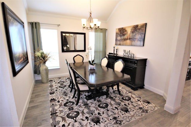 dining area featuring light hardwood / wood-style flooring, ornamental molding, and an inviting chandelier