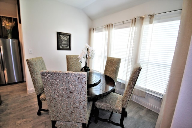 dining room with dark wood-type flooring and vaulted ceiling