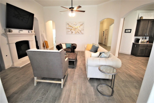 living room featuring ceiling fan, ornamental molding, and dark wood-type flooring