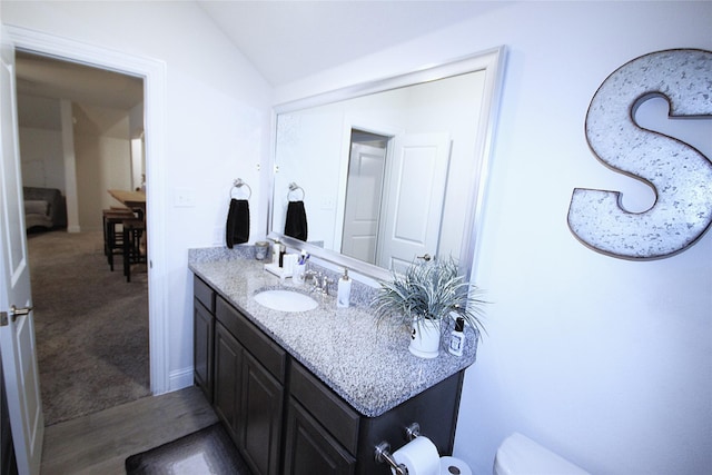 bathroom with vanity, toilet, and vaulted ceiling