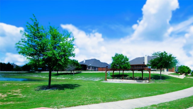 view of property's community with a yard, a water view, and a pergola