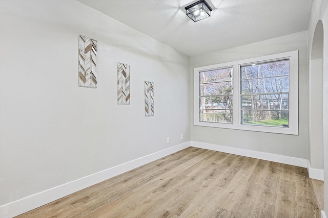 unfurnished room featuring light wood-type flooring and a textured ceiling