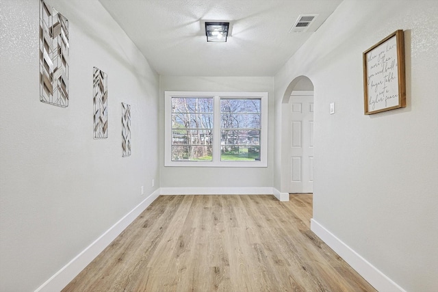 hallway with light wood-type flooring and a textured ceiling