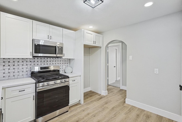 kitchen featuring white cabinets, decorative backsplash, light wood-type flooring, and stainless steel appliances