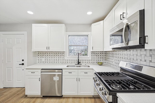 kitchen featuring white cabinetry, sink, light hardwood / wood-style floors, and appliances with stainless steel finishes