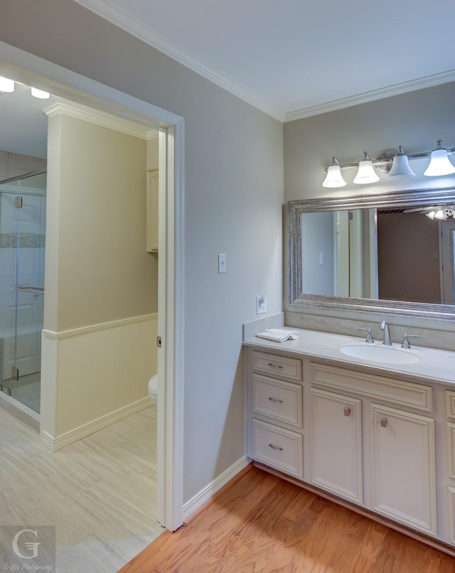 bathroom featuring toilet, wood-type flooring, a shower with shower door, and ornamental molding