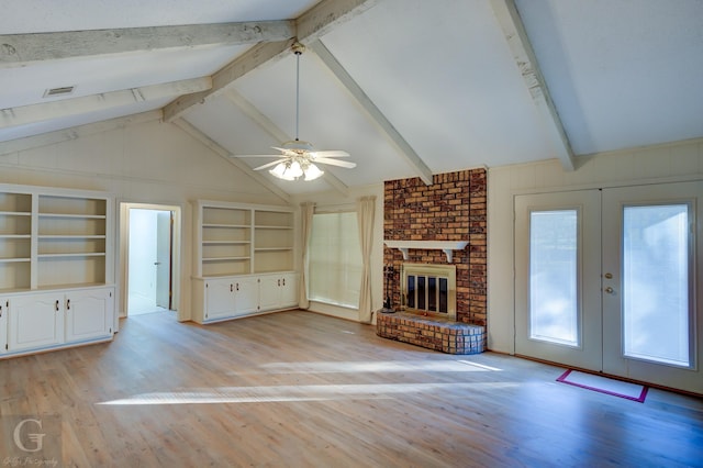 unfurnished living room featuring french doors, a brick fireplace, ceiling fan, light hardwood / wood-style flooring, and vaulted ceiling with beams