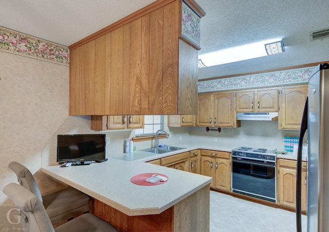 kitchen with kitchen peninsula, stainless steel fridge, black range with electric cooktop, a textured ceiling, and sink