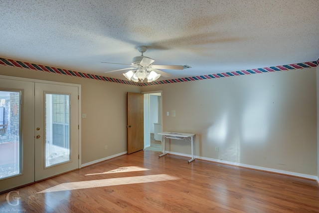 spare room with french doors, a healthy amount of sunlight, a textured ceiling, and light hardwood / wood-style floors