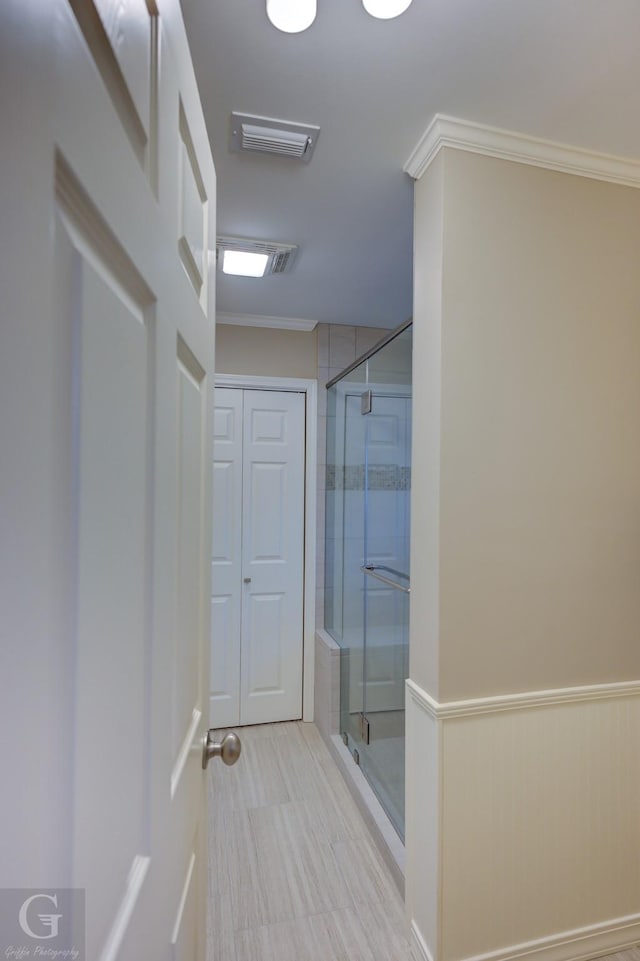 bathroom featuring ornamental molding and a shower with door
